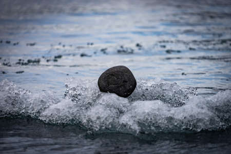 Small round black rock floating on icebergs, Iceland. concept of black sheep and lonelinessの写真素材
