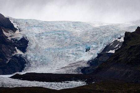 Glacier with ash in the ice with melted water and Icelandic landscapeの写真素材