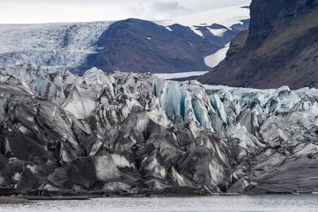 Glacier with ash in the ice with melted water and Icelandic landscapeの写真素材