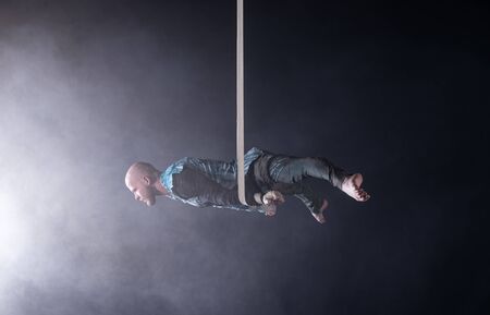 Circus artist on the aerial straps with costume on the black and smoked background.の写真素材