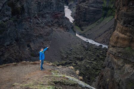 Caucasian young guy standing in over mountain and canyon background on the way of Laugavegur trail,...