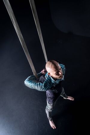 Circus artist on the aerial straps with costume on the black and smoked background.の写真素材