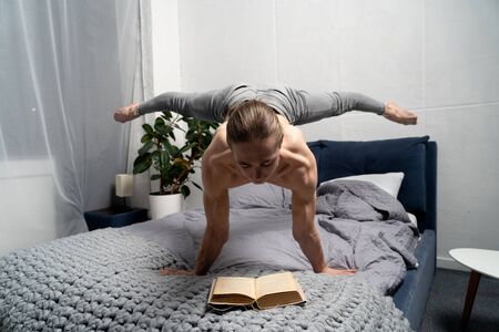 Gymnast reading book and keep balance on the hand in horizontal position. Concept of self-development, motivation and educationの写真素材