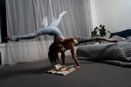 Couple spending time together reading book and making acrobatic balance at home. concept of self-development and creativity.の写真素材