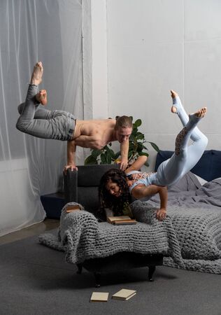 Couple spending time together reading book and making acrobatic balance at home. concept of self-development and creativity.の写真素材