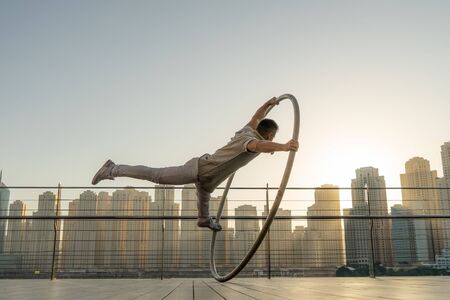 Cyr Wheel artist with cityscape background of Dubai during sunsetの写真素材