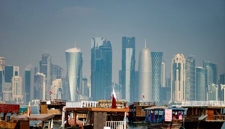 Panoramic view of modern skyline of Doha with old fishing boats foreground.の写真素材