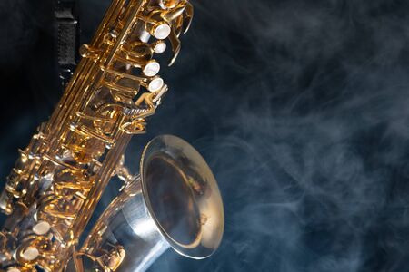 Golden shiny alto saxophone on black background with smoke. copy space.の写真素材