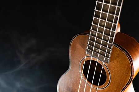 Hawaii ukulele guitar isolated against black background with smokeの写真素材