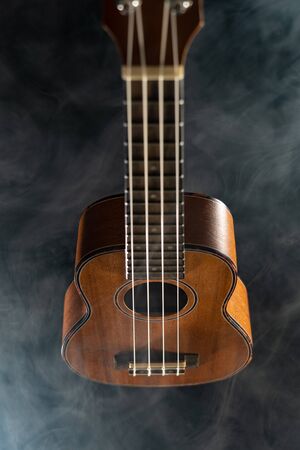 Hawaii ukulele guitar isolated against black background with smokeの写真素材