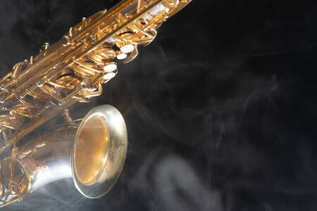 Golden shiny alto saxophone on black background with smoke. copy space.の写真素材