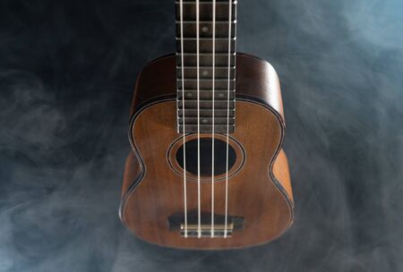 Hawaii ukulele guitar isolated against black background with smokeの写真素材