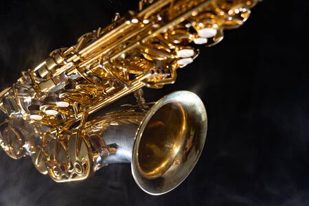Golden shiny alto saxophone on black background with smoke. copy space.の写真素材