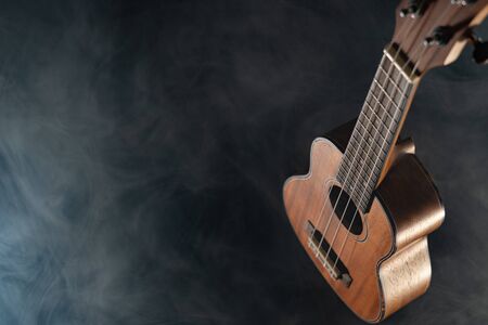 Hawaii ukulele guitar isolated against black background with smokeの写真素材
