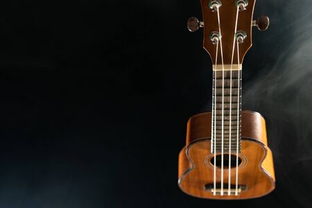 Hawaii ukulele guitar isolated against black background with smokeの写真素材
