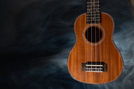 Hawaii ukulele guitar isolated against black background with smokeの写真素材