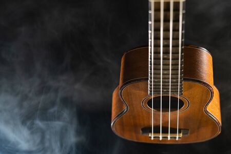 Hawaii ukulele guitar isolated against black background with smokeの写真素材