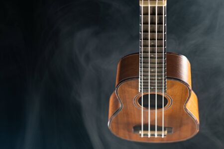 Hawaii ukulele guitar isolated against black background with smokeの写真素材