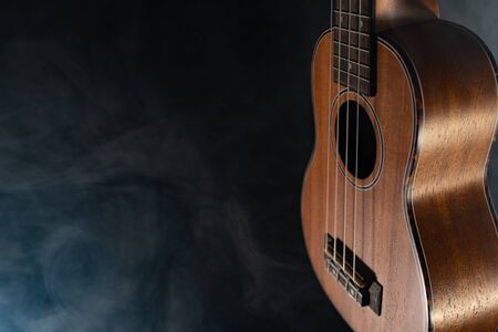 Hawaii ukulele guitar isolated against black background with smokeの写真素材