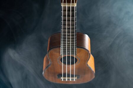 Hawaii ukulele guitar isolated against black background with smokeの写真素材