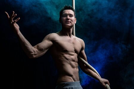 Muscular male circus artist with Cord Lisse on black and smoked backgroundの写真素材