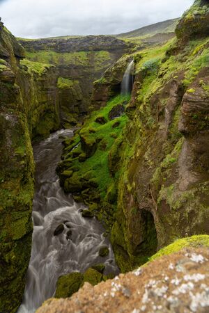 Beautiful river with tiny waterfall in Iceland surrounded by green cliff.の写真素材