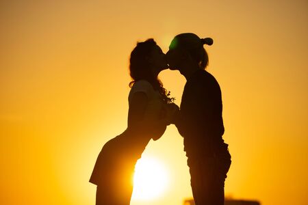 Silhouette of young kissing couple over sunset backgroundの写真素材