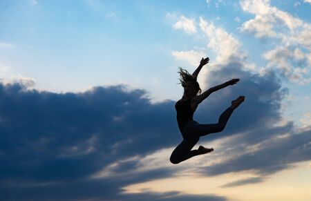 Young woman dancer on outdoor sunrise backgroundの写真素材