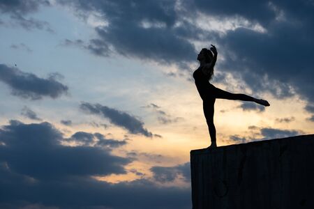 Young woman dancer on outdoor sunrise background. Concept of freedom, brave and happy lifestyleの写真素材