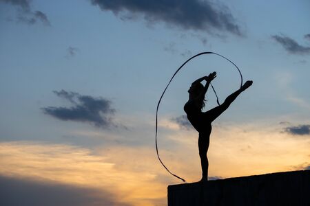 Professional gymnast woman dancer with ribbon on sky backgroundの写真素材