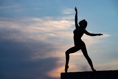 Well shaped woman dancer on outdoor sunrise background. Concept of freedom and happy lifestyle.の写真素材
