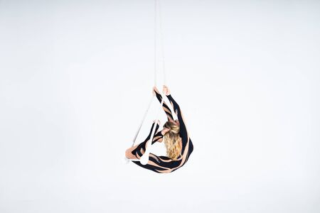 Young woman gymnast wearing black costume on trapeze on white background.の写真素材