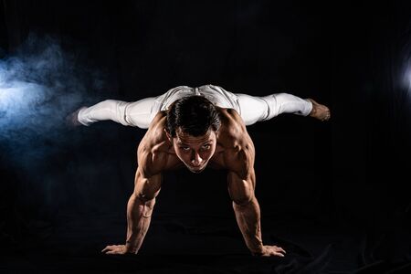 Muscular man making planche on black black backgroundの写真素材
