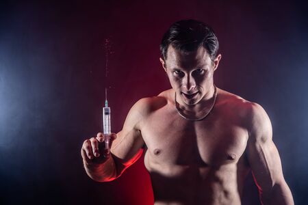 Bodybuilder holding big syringe with injection. concept of steroid in the sport and addictionの写真素材