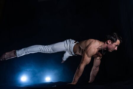 Muscular man making planche on black black backgroundの写真素材