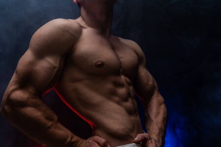 Muscular man showing muscles isolated on the black background. Concept of healthy lifestyleの写真素材