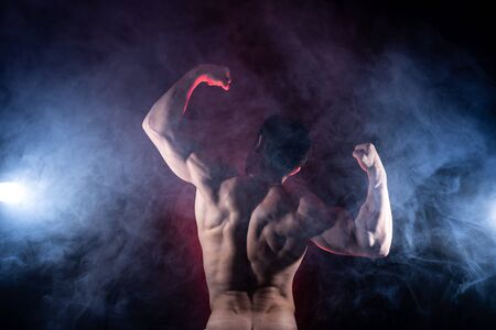 Muscular man showing muscles isolated on the black background. Concept of healthy lifestyle and healthcareの写真素材