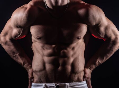 Muscular man showing muscles isolated on the black background. Concept of bodybuilding and creating your body at gymの写真素材
