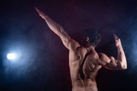 Muscular man showing muscles isolated on the black background. Concept of healthy lifestyle and healthcareの写真素材