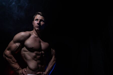 Muscular man showing muscles isolated on the black background. Concept of bodybuilding and creating your body at gymの写真素材