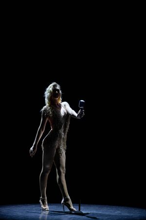Silhouette of Beautiful good shaped blond woman singing on the stage with microphoneの写真素材