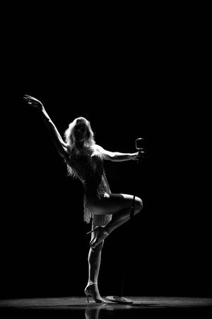 Silhouette of Beautiful good shaped blond woman singing on the stage with microphoneの写真素材