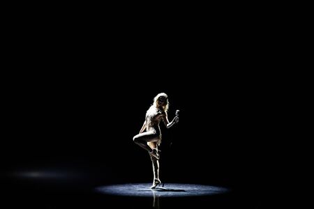 Silhouette of Beautiful good shaped blond woman singing on the stage with microphoneの写真素材