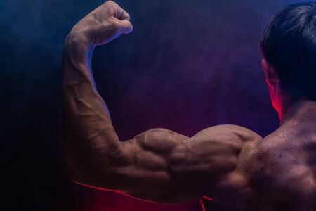 Muscular man showing muscles isolated on the black background close up. Concept of healthy lifestyle.の写真素材