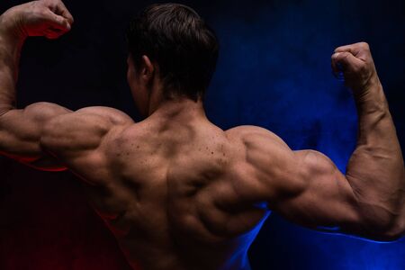 Muscular man showing muscles isolated on the black background.healthy lifestyleの写真素材