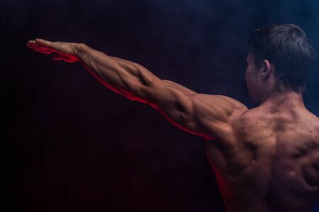 Muscular man showing muscles isolated on the black background.healthy lifestyleの写真素材