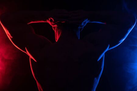 Muscular man showing muscles isolated on the black background with colored smoke. Concept of healthy lifestyle.の写真素材