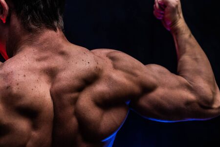 Muscular man showing muscles isolated on the black background with colored smoke. Concept of healthy lifestyle.の写真素材