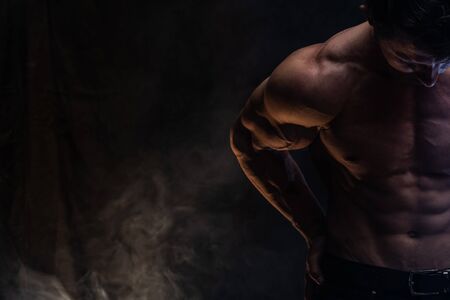 Muscular man showing muscles isolated on the black background.healthy lifestyleの写真素材