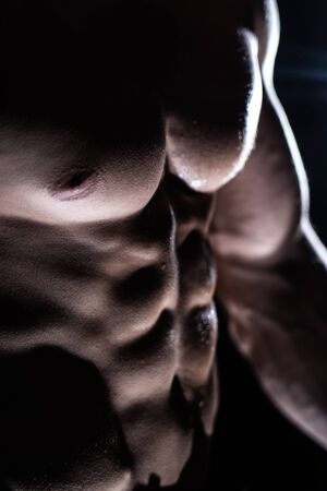 Muscular man showing muscles isolated on the black background. Concept of healthy lifestyleの写真素材